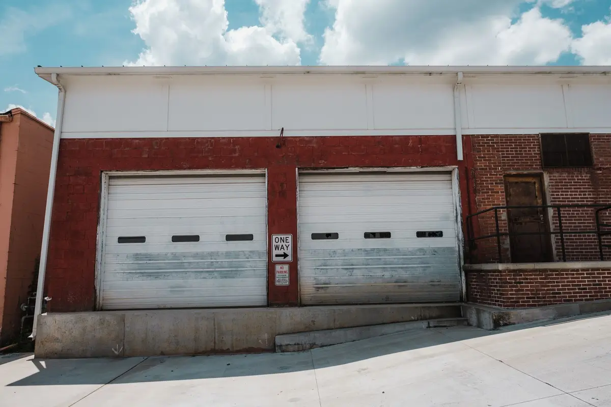 Red-brick building with two white roll-up garage doors and a loading dock
