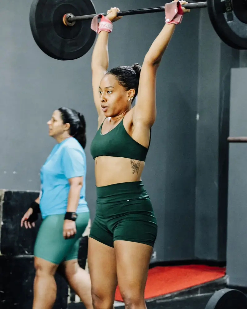 Woman standing tall with a loaded barbell locked out overhead
